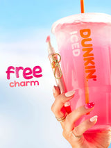 Hand holding a pink Dunkin' drink with a free charm offer against a blue gradient background