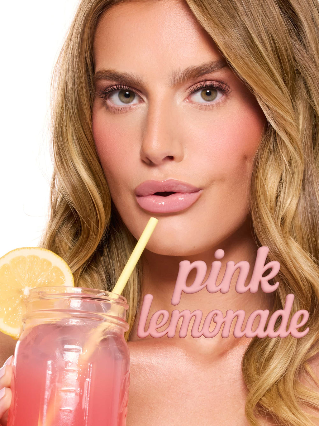 Close-up of a woman holding a mason jar of pink lemonade, lips poised at a yellow straw, studio-lit white background, glossy makeup. Text: pink lemonade