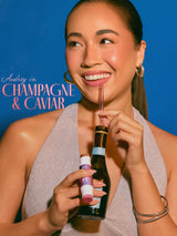 Woman drinking from a bottle with a straw against a blue background with tarte maracuja juicy double ended multi stick 