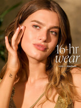 Woman with long brown hair and a gold top, with text '16-hr wear neillean in medium' on a blurred background wearing tarte CC serum 