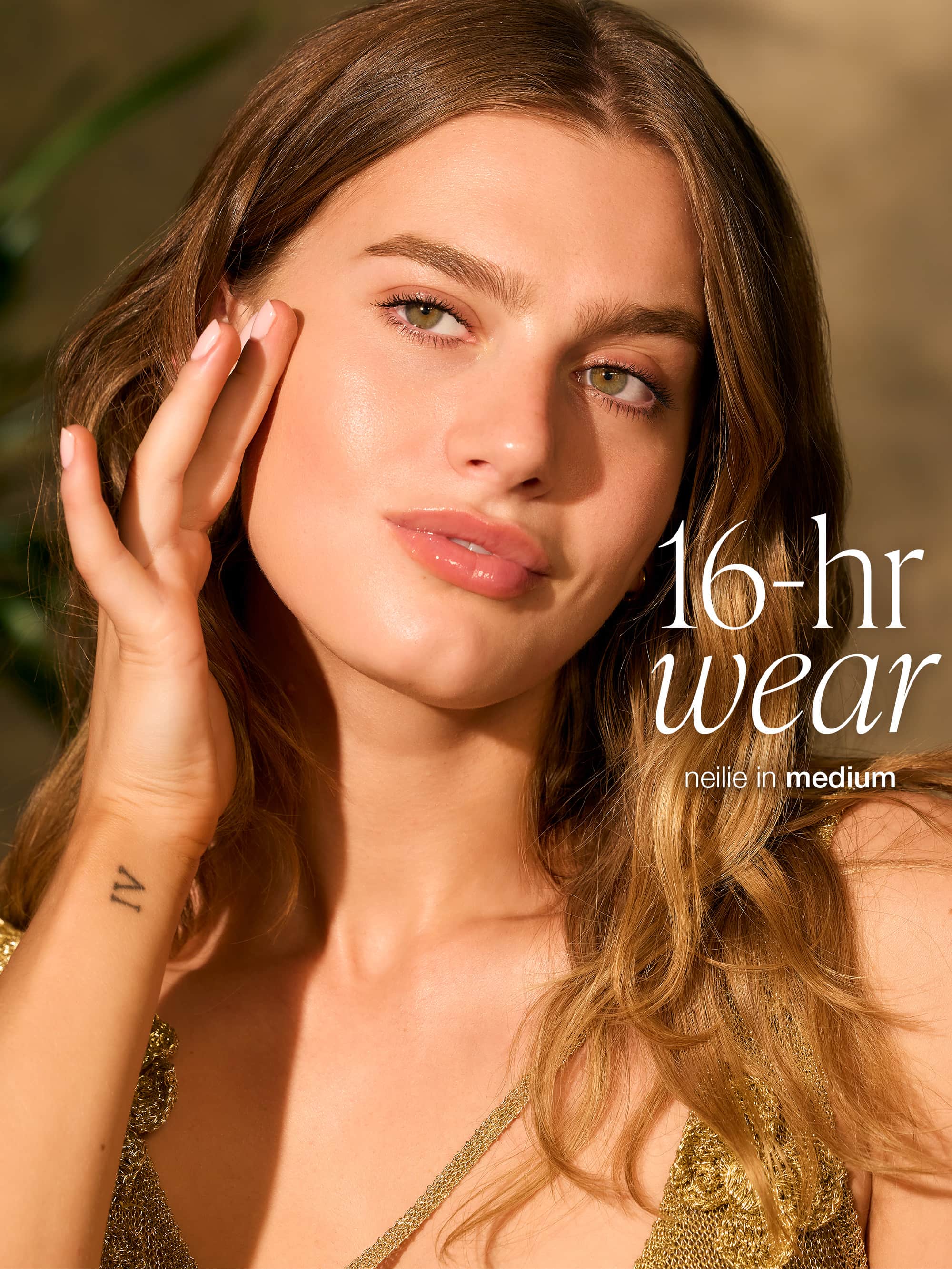 Woman with long brown hair and a gold top, with text '16-hr wear neillean in medium' on a blurred background wearing tarte CC serum 