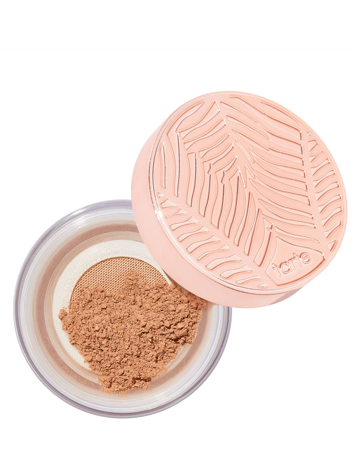 Open container of brown powder with a pink lid on a white background