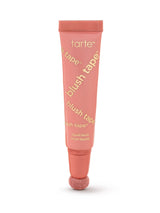 A coral-pink Tarte blush tube stands upright, applicator sponge at the base, on a white background. Text visible: tarte; blush tape™ (repeated diagonally); liquid blush; blush liquide.