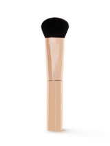 Makeup brush with black bristle head and beige handle on a white background