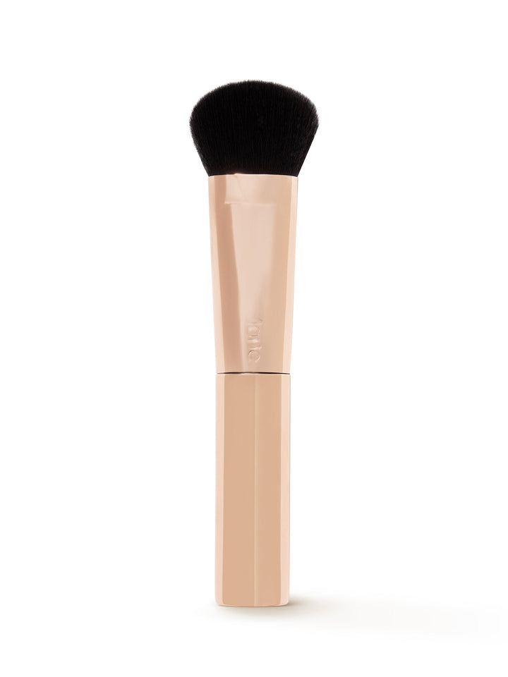 Makeup brush with black bristle head and beige handle on a white background