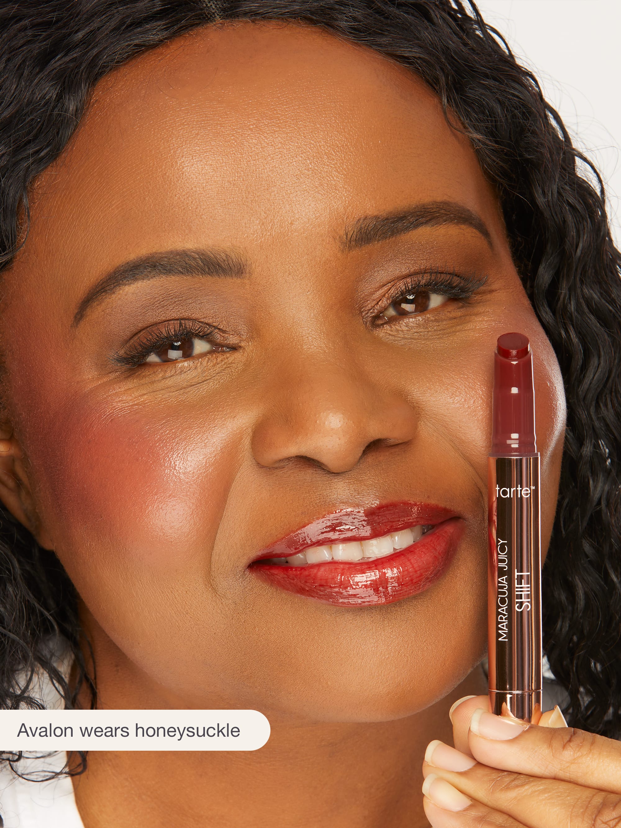 Woman holding a Tarte makeup product with a close-up of her face.