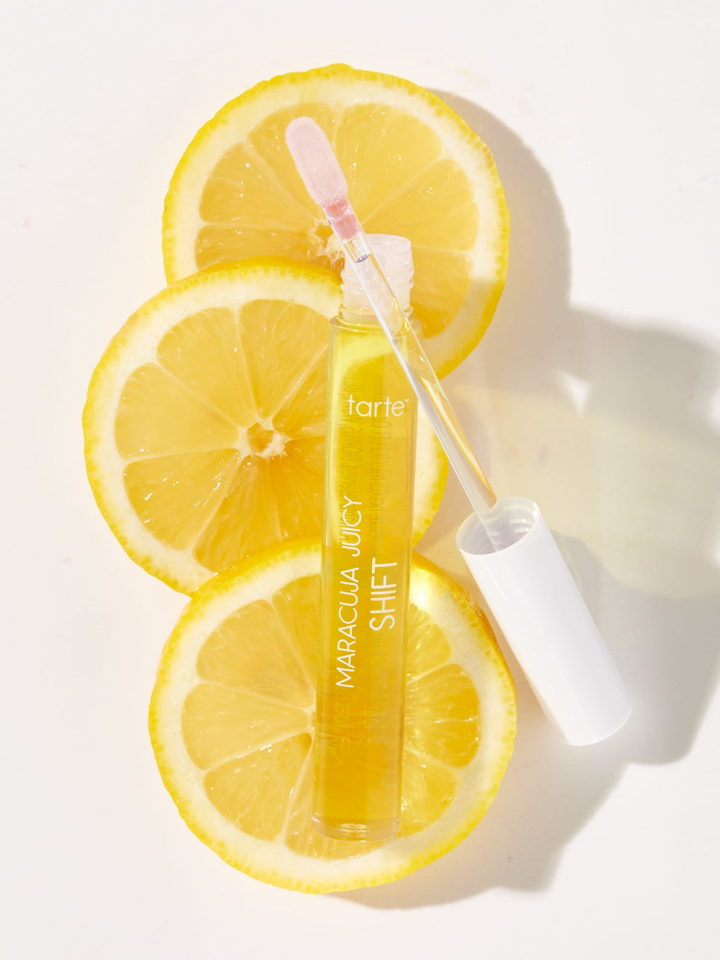 Tarte Maracuja Juicy Shift serum bottle with applicator on lemon slices against a white background
